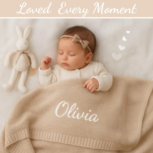 Beige knit baby blanket embroidered with the name Olivia, on a sleeping newborn